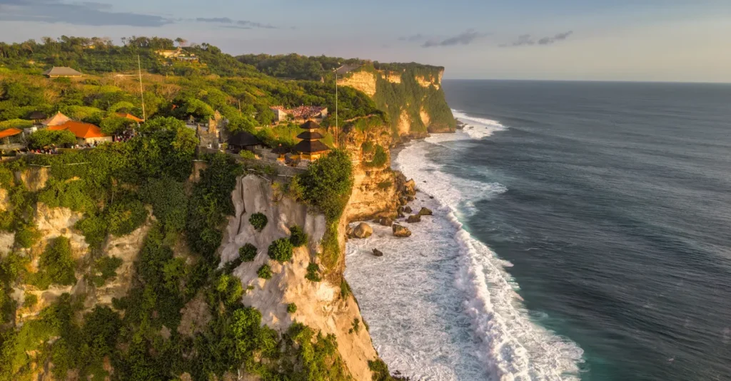 Indonésie à deux (et Bali en base) : le guide concret pour éviter les galères et viser le romantisme A breathtaking view of Uluwatu's coastal cliffs in Bali during a golden sunset, showcasing nature's beauty.