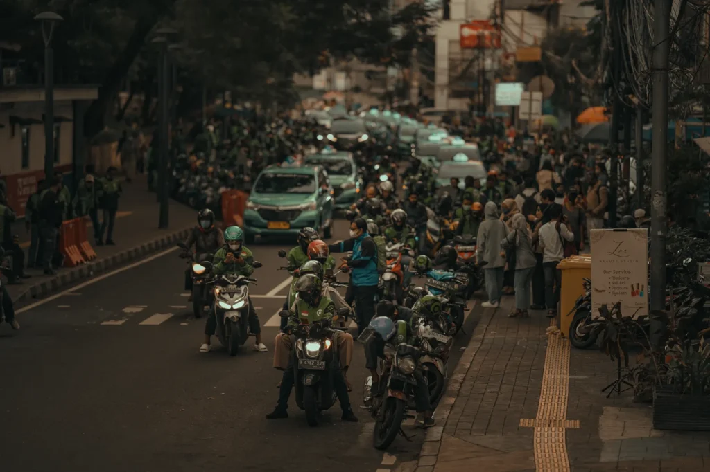 A bustling street in Jakarta filled with motorbikes and people on a busy day.