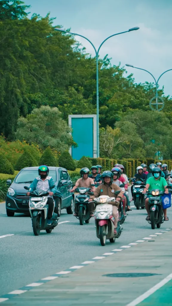 A busy urban street with motor scooters and vehicles under a clear sky.