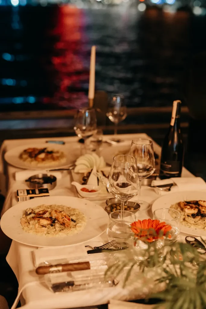 A candlelit riverside dinner setup with gourmet plates and elegant decor, offering a warm, inviting atmosphere.