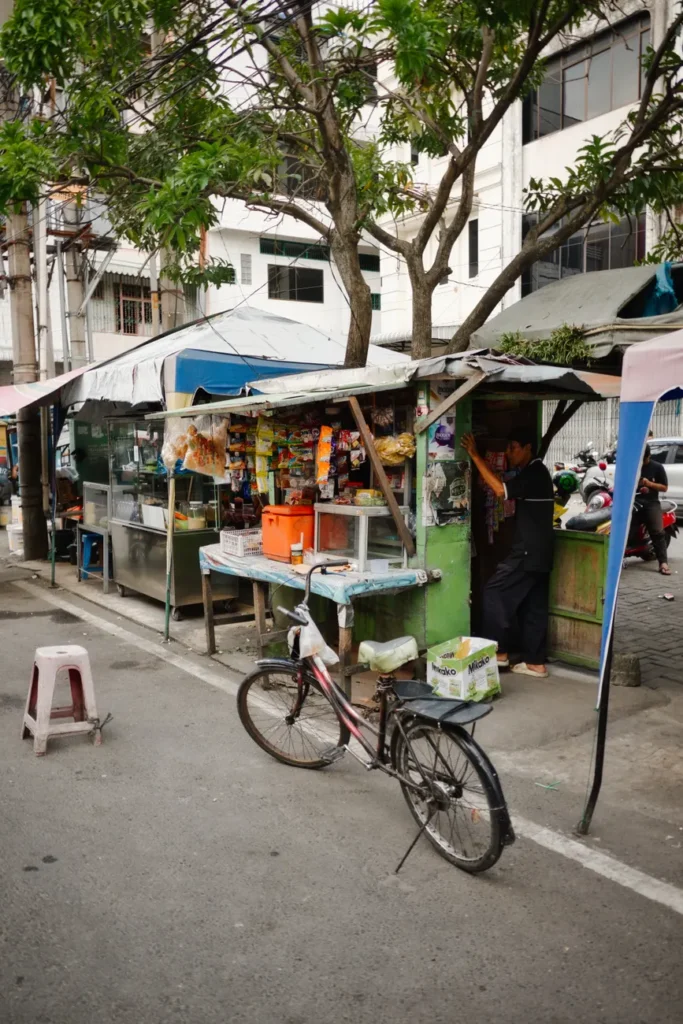 A colorful street food vendor stall in Medan, displaying local snacks and goods.