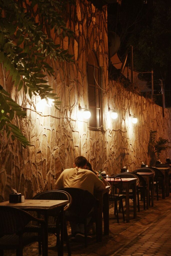 A couple enjoys a cozy night at an outdoor restaurant in İzmir, Türkiye, with ambient lights.