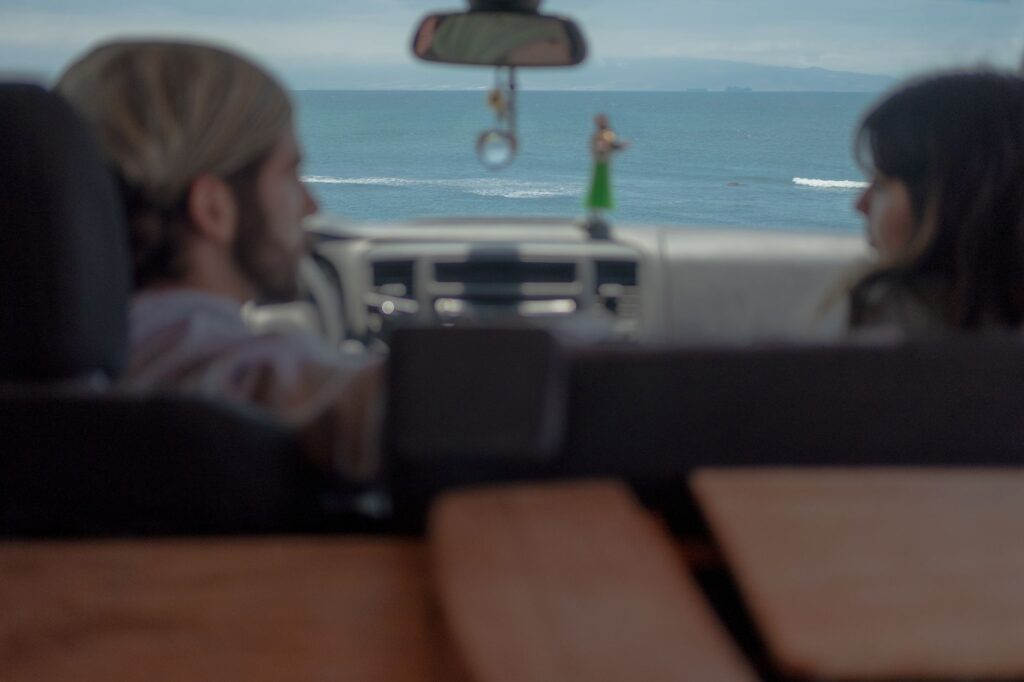 A couple enjoys a scenic ocean view from their car, featuring a relaxed atmosphere.