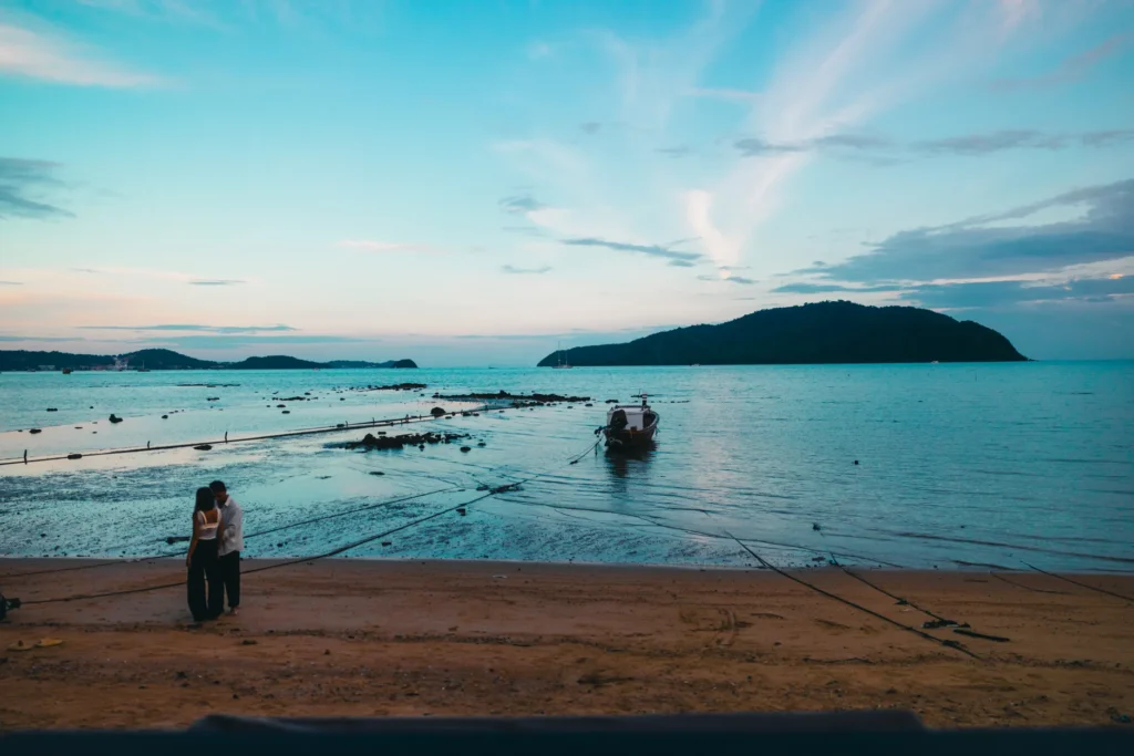 A couple shares a romantic moment on a beach in Phuket, Thailand with a serene sea backdrop.