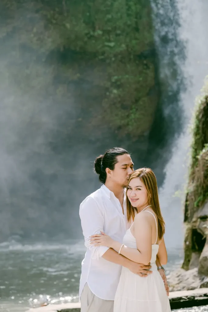 A couple sharing a tender moment in front of a stunning waterfall