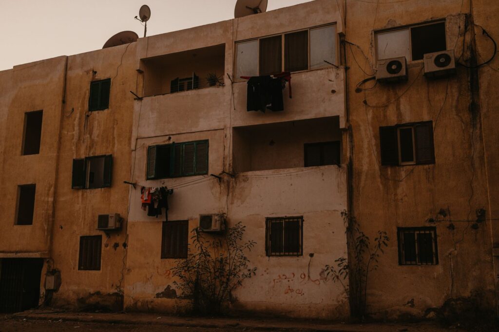 A decaying apartment building in Egypt with clotheslines and air conditioning units visible.