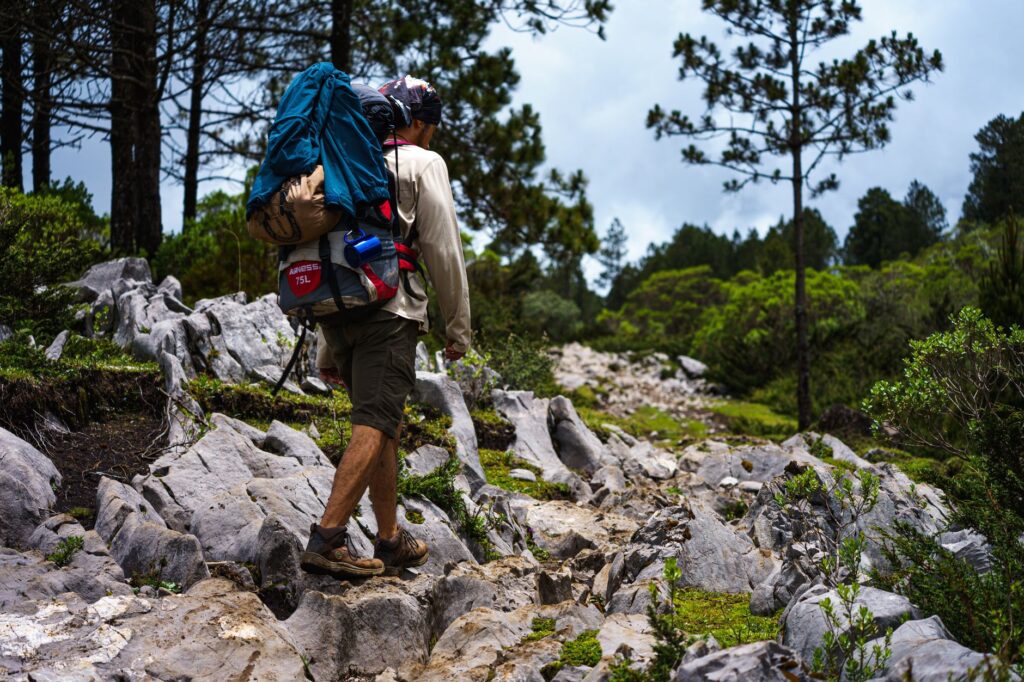 A lone hiker traverses a rocky forest trail in scenic Quiché, Guatemala.