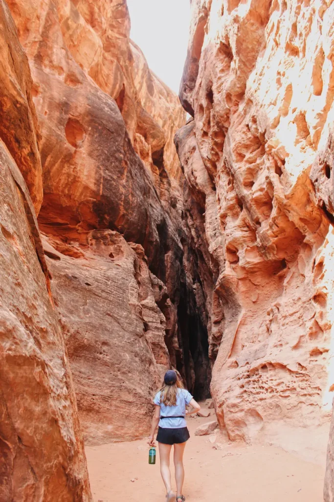 A lone hiker walks through the stunning eroded rock formations of Jenny's Canyon in Utah.