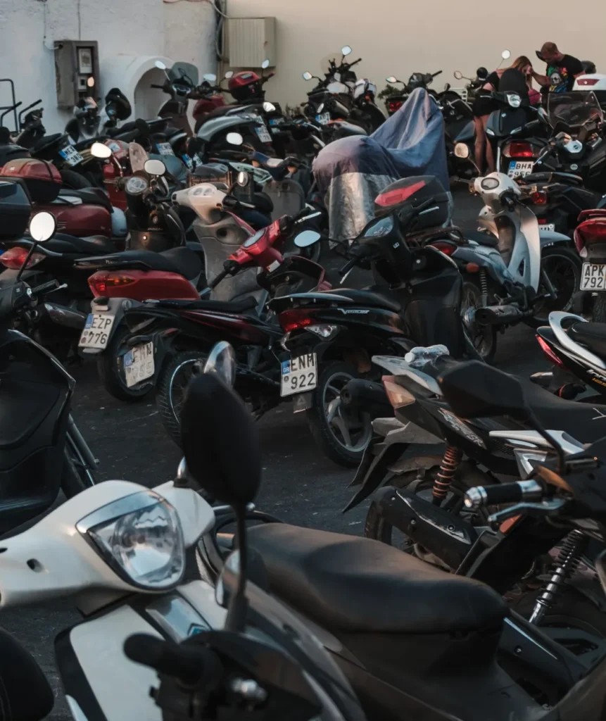 A packed parking area filled with various parked motorcycles during the evening.
