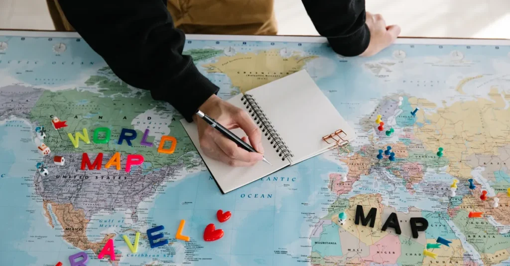 Combien de pays viser à deux en 2026 ? Le guide concret (sans piège de carte) A person writing in a notebook on a world map, planning a travel journey with colorful markers and a pen.