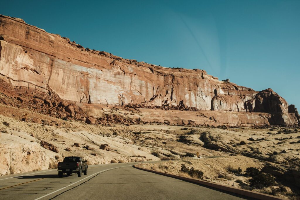 A pickup truck driving along a scenic road in Arches National Park, Utah, USA.