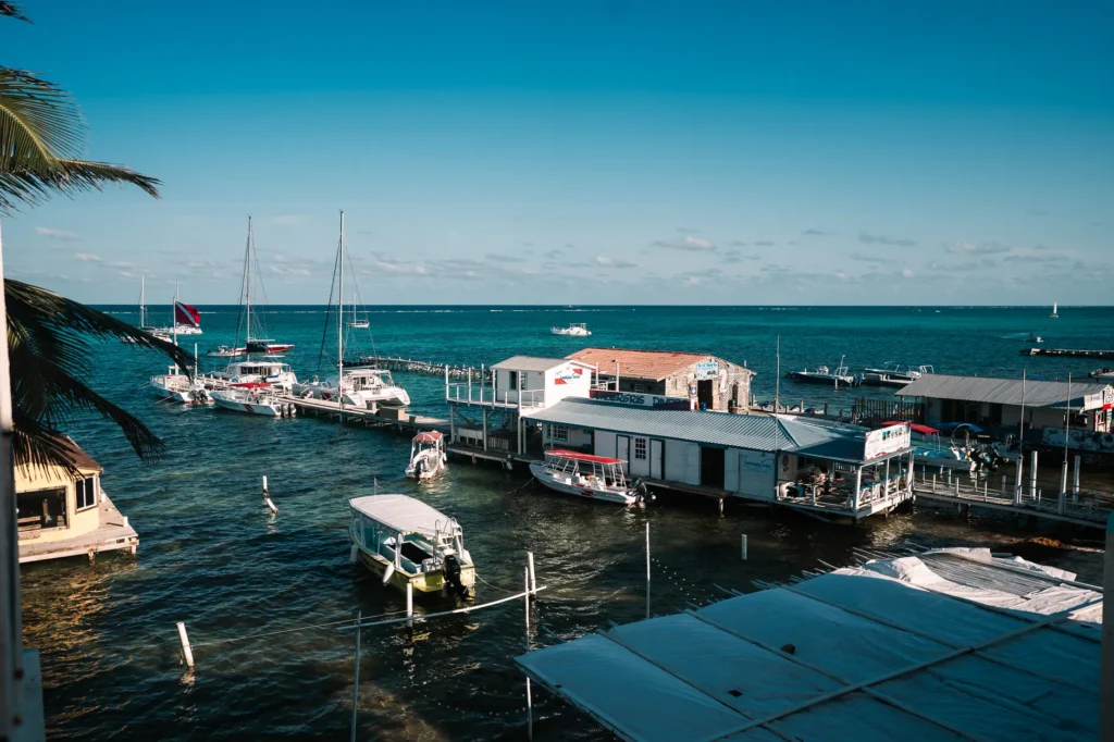A picturesque marina with sailboats and clear blue waters under a sunny sky, offering a tranquil seaside scene.