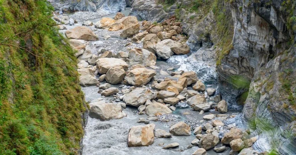 Taroko à deux : le guide concret pour visiter la Gorge de Taroko sans se cramer A picturesque view of a rocky river gorge in Taroko National Park, Taiwan, with rugged cliffs and flowing water.