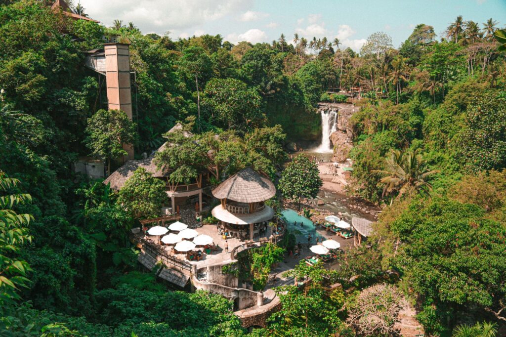 A serene tropical resort nestled in a lush forest in Ubud, Bali, featuring a stunning waterfall.