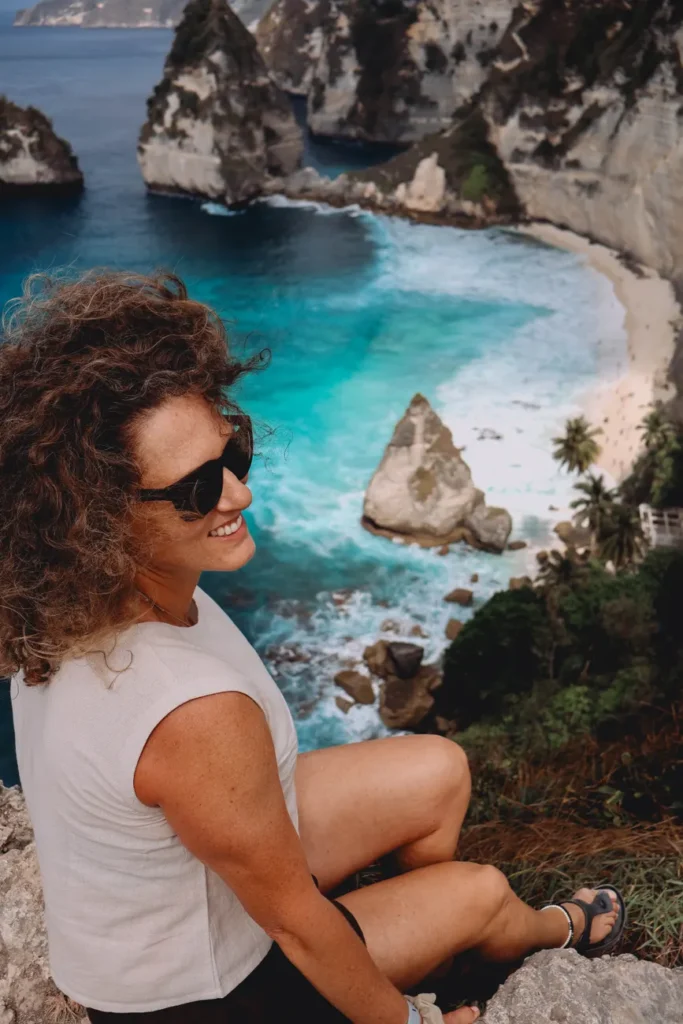 A smiling woman enjoys the stunning coastal view at Nusa Penida, Bali, Indonesia.