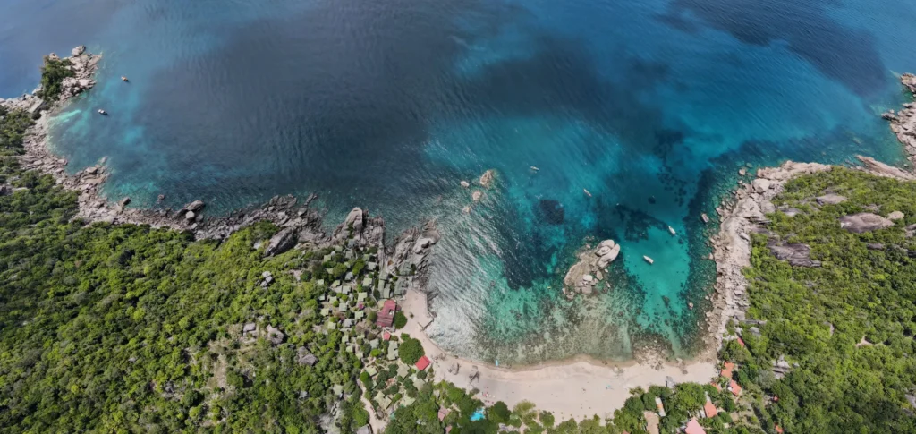A stunning aerial shot of a tropical coastline with lush greenery and crystal clear waters.