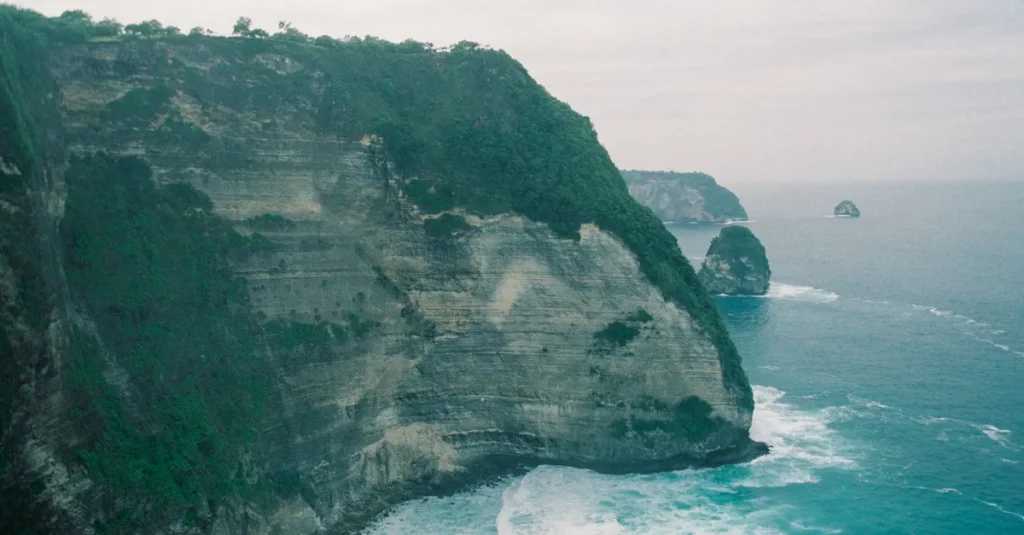 Nusa Penida en couple : dormir dans la treehouse Rumah Pohon Molenteng (sans se rater) A stunning aerial view of Bali's coastal cliffs, showcasing the dramatic sea and lush vegetation.