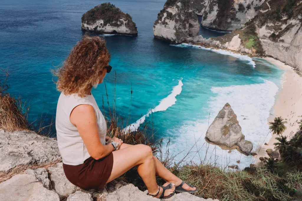 A woman enjoys a breathtaking ocean view from a clifftop on Nusa Penida, Bali.