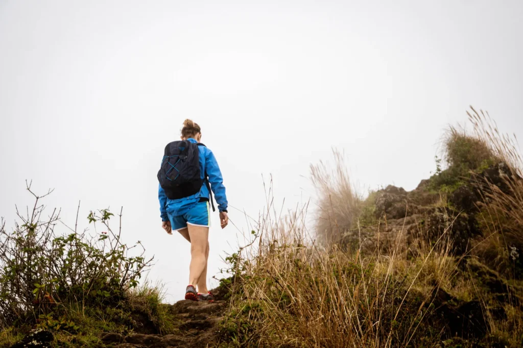 A woman hiking on a misty trail in Hawaii, showcasing nature and adventure.