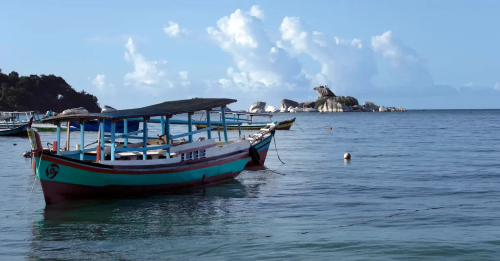 A wooden fishing boat anchored on tranquil sea waters under a clear blue sky.