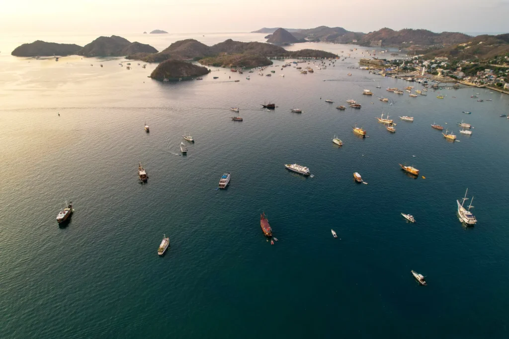Aerial view of boats scattered across Labuan Bajo's scenic waters at sunset.