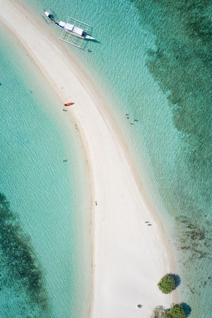 Aerial view showcasing a pristine white sand beach with turquoise water in the Philippines.