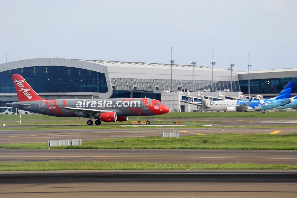 AirAsia plane preparing for takeoff at a bustling airport terminal. Perfect for travel-themed projects.