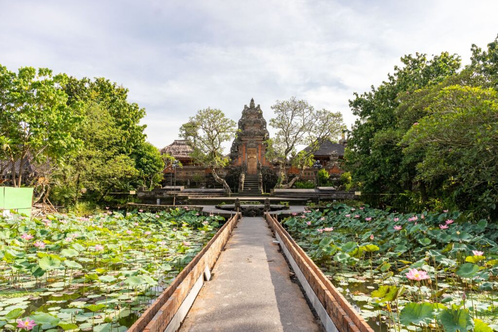 Beautiful Balinese temple surrounded by lush greenery and lotus pond, showcasing tropical architecture.