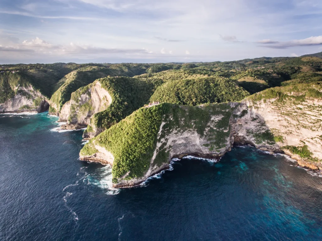 Breathtaking aerial view of the lush cliffs and turquoise waters of Nusa Penida, Bali.