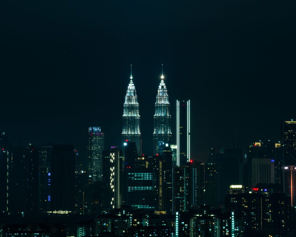 Breathtaking view of Kuala Lumpur's skyline at night featuring the iconic Petronas Towers illuminated against a dark sky.