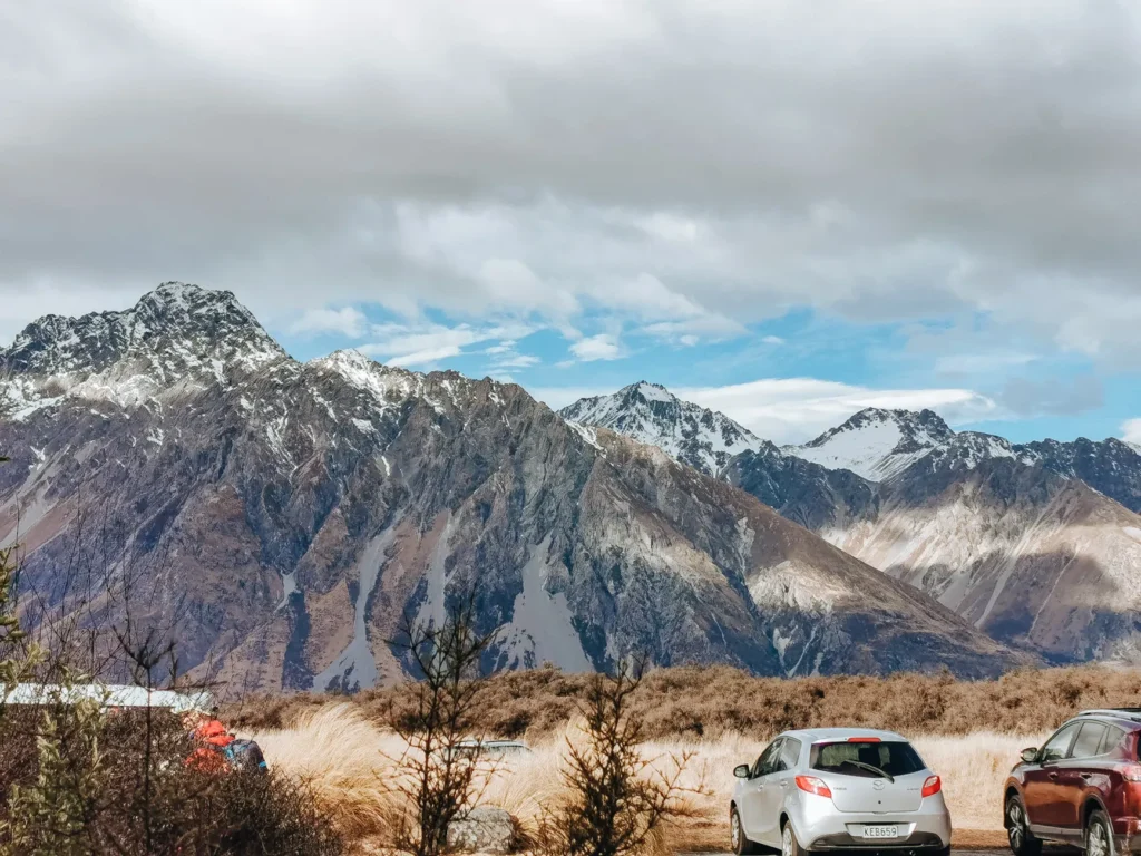 Breathtaking view of mountains in Aoraki Mount Cook National Park, with cars in the foreground.