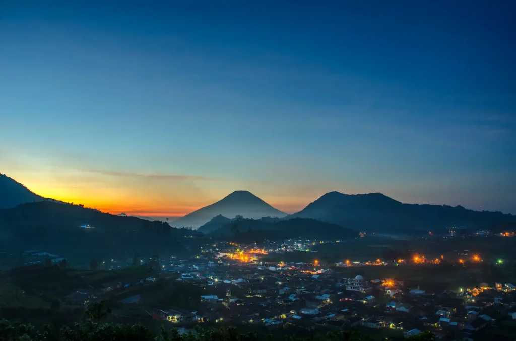 Captivating dawn view of a town in Jawa Tengah with mountain silhouettes and vibrant lights.