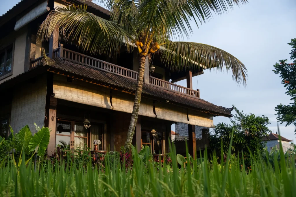 Charming Balinese architecture surrounded by tropical greenery and palm trees, capturing a serene vacation vibe.