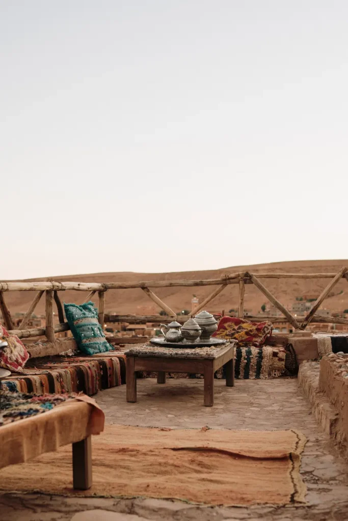 Charming rooftop terrace with Moroccan decor in Fes at sunset, featuring traditional seating and a scenic view.