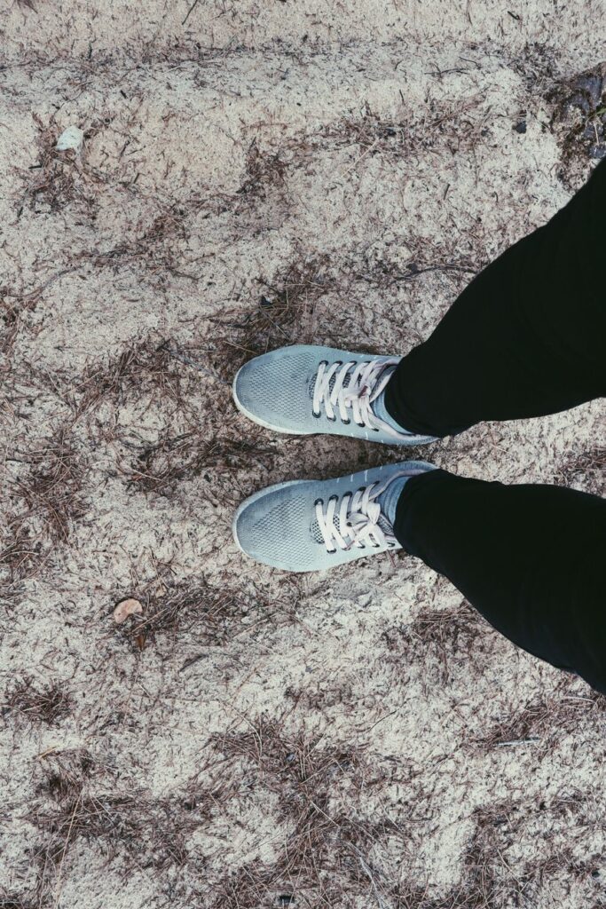 Close-up of sneakers on sandy ground outdoors, ideal for lifestyle or travel themes.