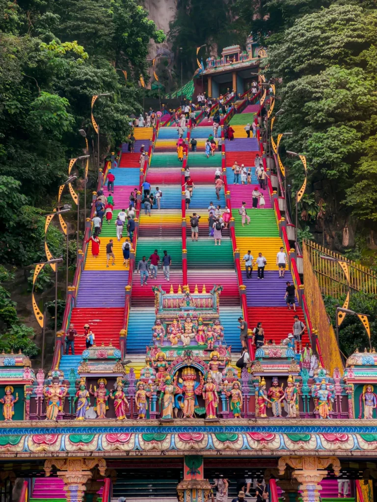 Colorful stairs at Batu Caves, Malaysia with visitors climbing. Iconic cultural landmark.