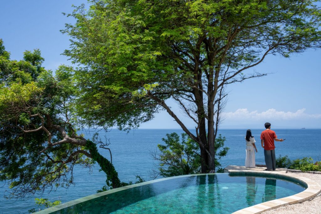 Couple enjoys the scenic ocean view from a luxurious infinity pool in Bali, Indonesia.