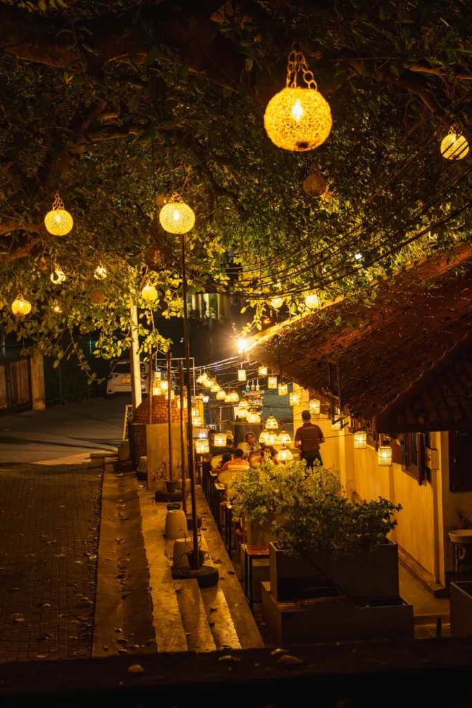 Cozy outdoor café illuminated by warm lights under a tree in Galle, Sri Lanka.