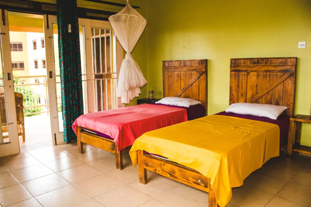 Cozy twin bedroom in Kampala, Uganda with vibrant bedding and a mosquito net, perfect for a tropical stay.