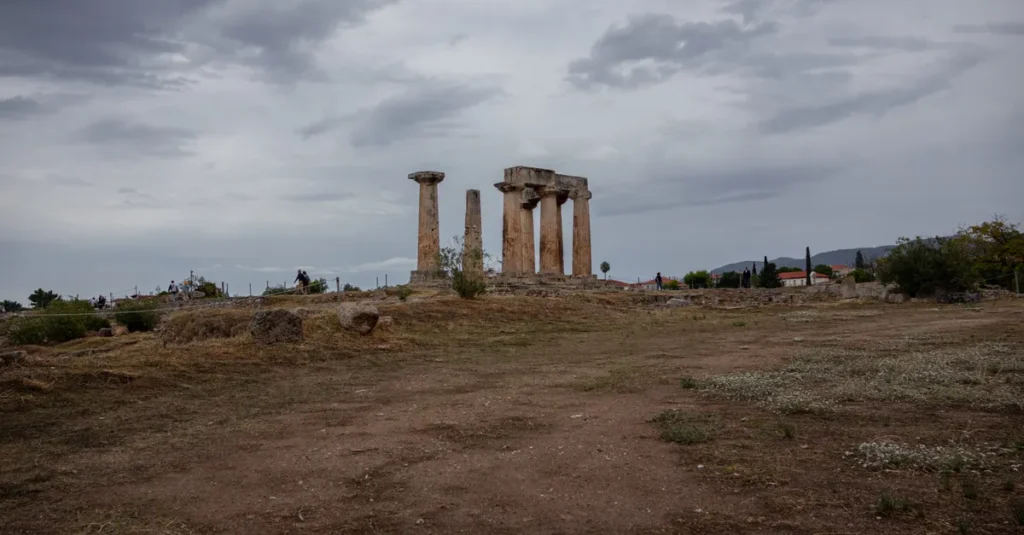 Ancient Corinth en couple depuis Athènes : le day-trip concret (sans vous cramer) Discover the serene ruins of the Temple of Apollo in Ancient Corinth, Greece, under cloudy skies.