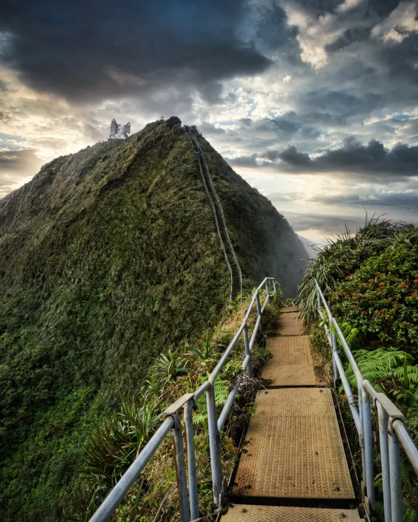 Dramatic clouds over Oahu's Stairway to Heaven, featuring lush mountains and scenic pathways.