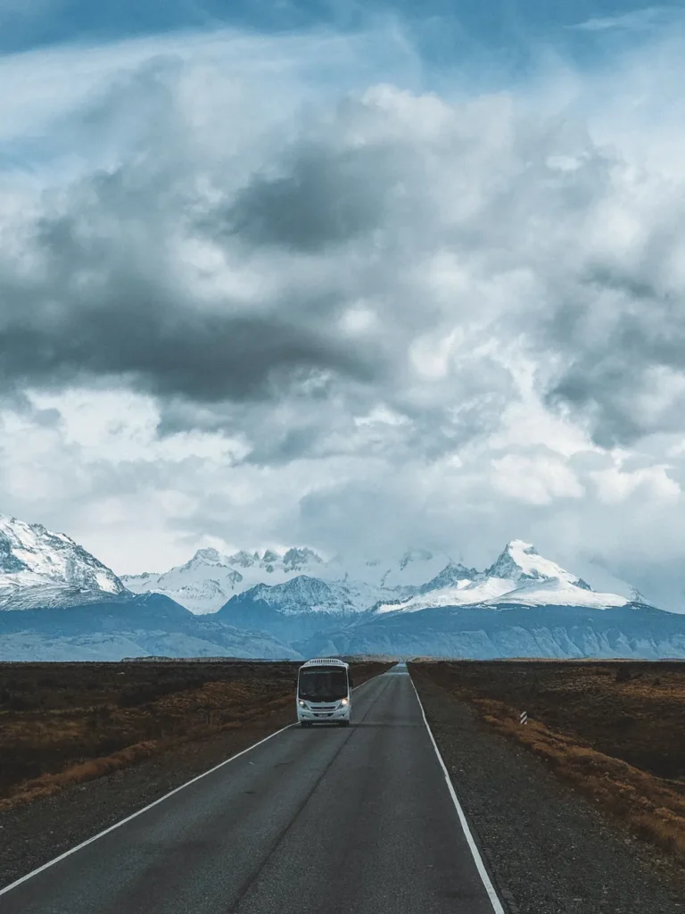 Dramatic landscape of a bus on a remote road leading to mountains in Patagonia.