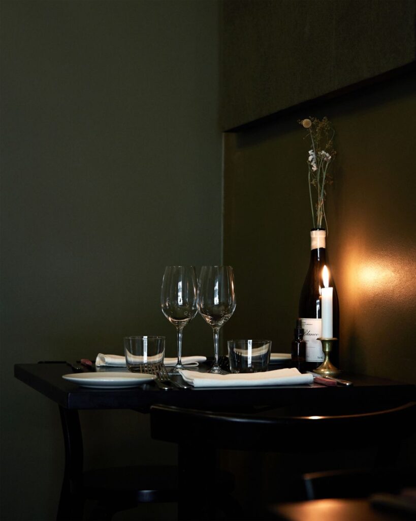 Elegant restaurant table with wine glasses, candle, and bottle, evoking a romantic evening ambiance.