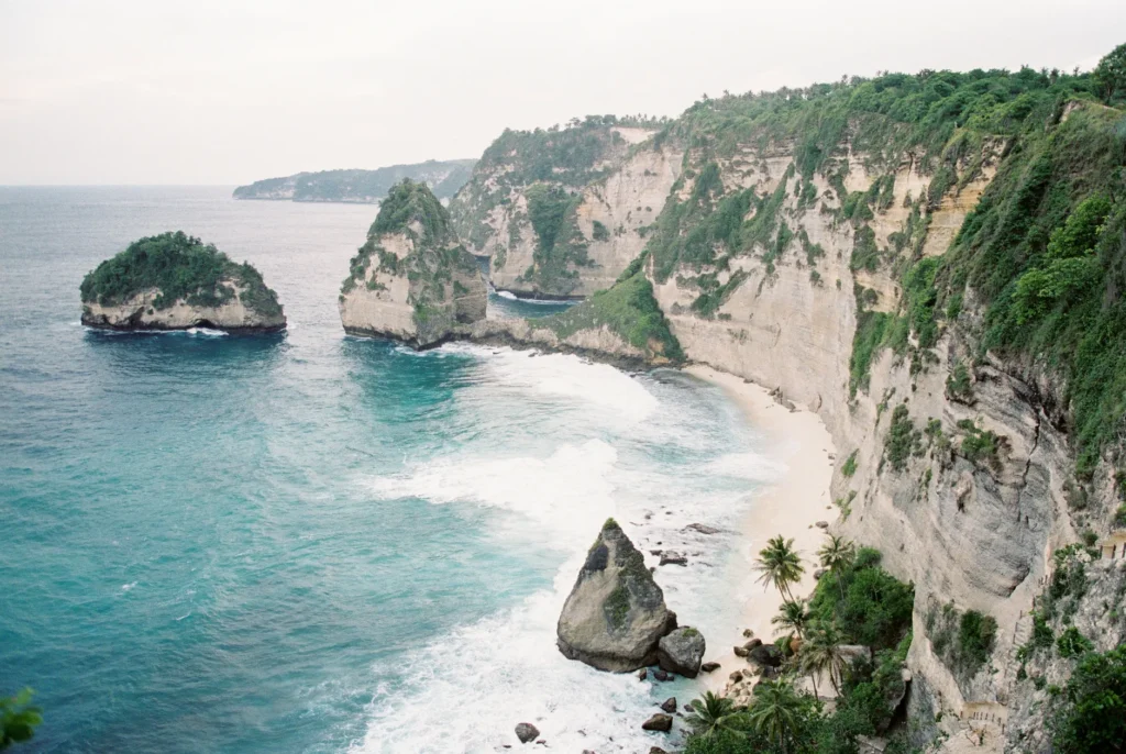 Experience the breathtaking view of Bali's Atuh Beach with its dramatic cliffs and serene ocean waves.