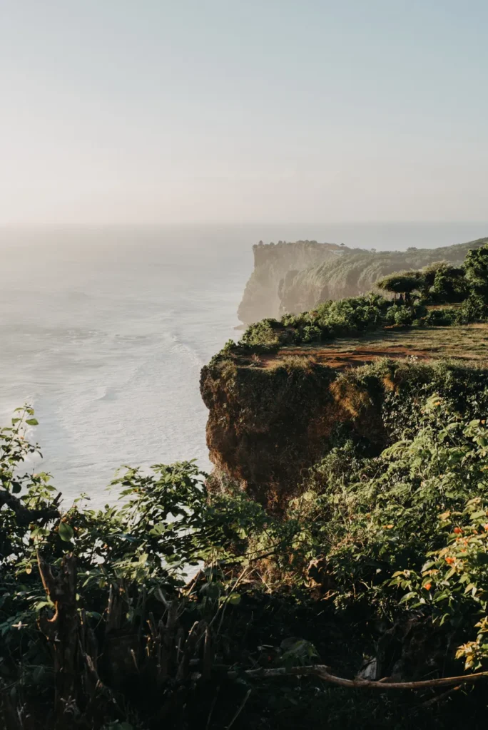 Explore the stunning coastline cliffs of Bali, Indonesia, with lush greenery and crashing waves.