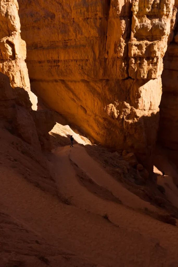 Explore the stunning red rock formations of Bryce Canyon, Utah, with a lone hiker on a sunlit trail.