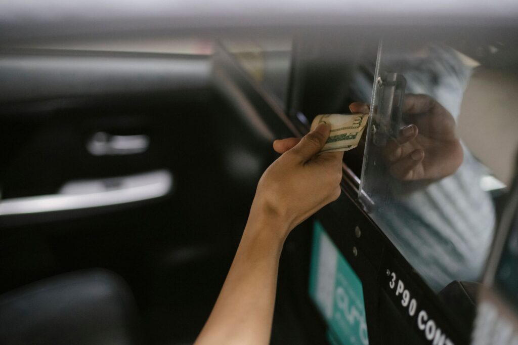 From above of crop anonymous client paying in cash for taxi trip to ethnic driver after arrival