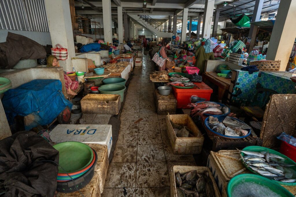 Indonesian fish market filled with seafood and vibrant goods, captured indoors.