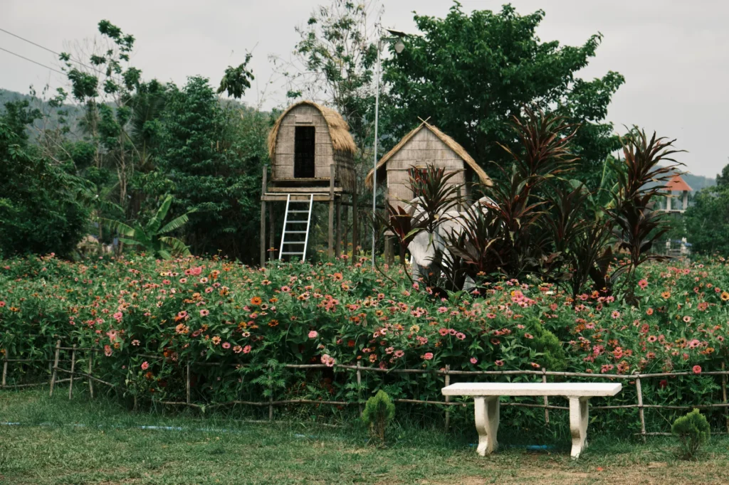 Lush tropical garden with wooden huts and vibrant flowers, ideal for travel and nature themes.