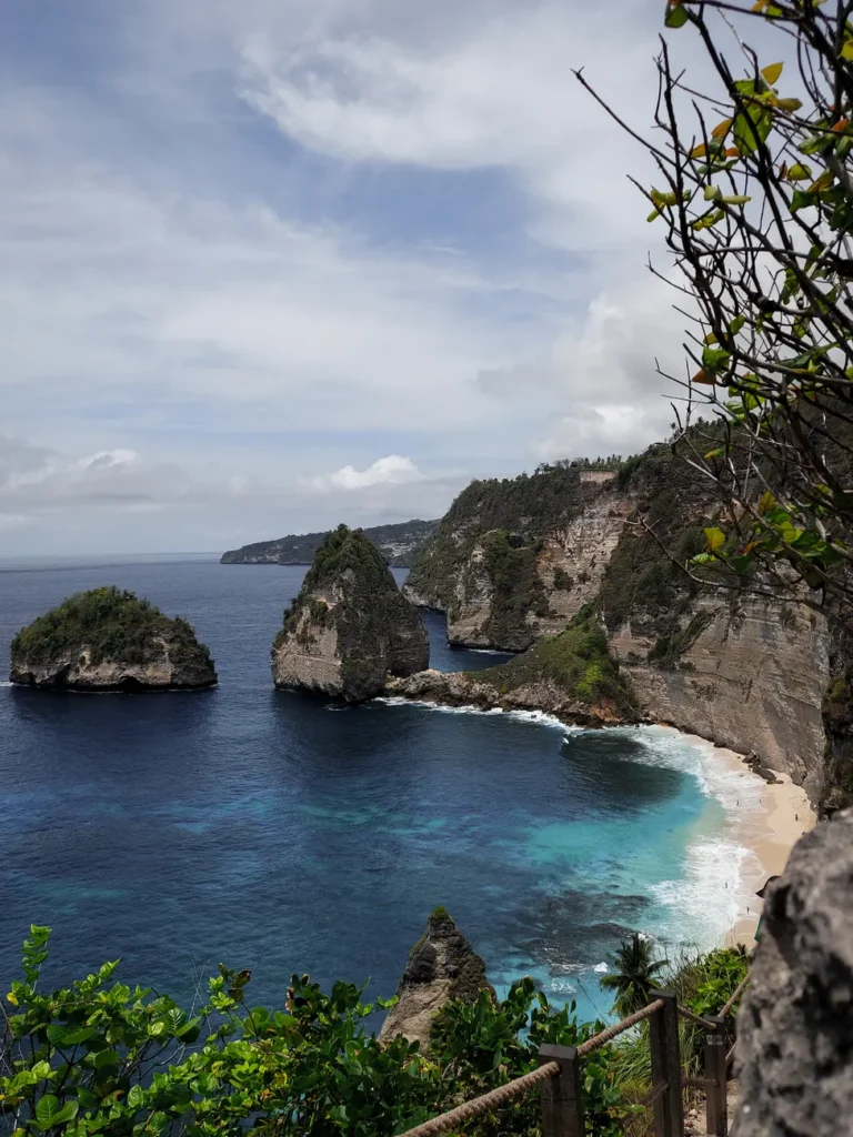 Majestic cliffs and ocean view at Nusa Penida, Bali, featuring lush greenery and clear blue waters.